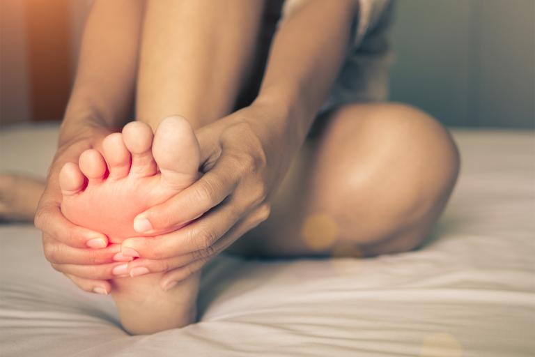 A woman massaging pain in her foot